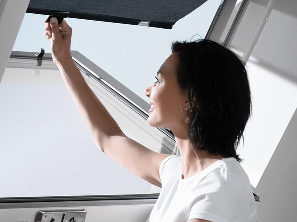 VELUX Hitzeschutz-Markise wird am geöffneten Dachfenster eingehängt
