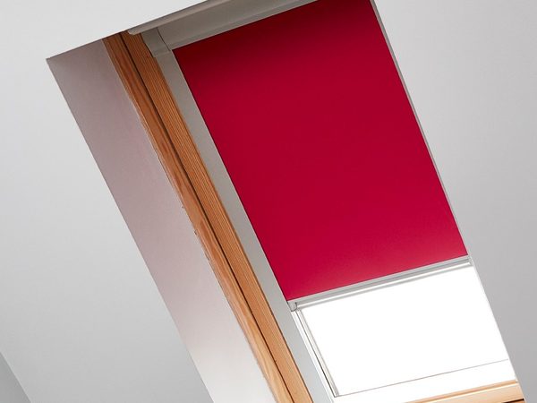 Rotes Verdunkelungsrollo mit Führungsschienen an einem Holz-Dachfenster